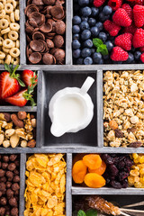 Variety of cold quick breakfast cereals with berries in old gray wooden box and other ingredients for breakfast, healthy eating concept, top view.