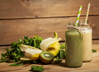 Freshly blended green and banana smoothies in glass bottles with straws.