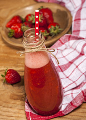 Strawberry smoothie or milkshake in bottle on wooden rustic background.