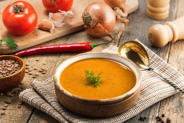Lentil soup in a rustic bowl on a cotton canvas tablecloth. Healthy vegetarian food on an old wooden table. Top view.