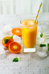 Orange juice with ice and tangerines on white background. Free space for your text. Copyspace. Cold beverage for hot summer day.