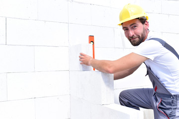 Portrait freundlicher Bauarbeiter auf der Baustelle - Mauern einer Hauswand 