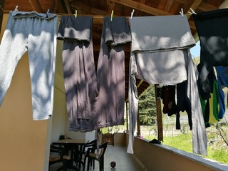 Frisch gewaschene graue Hosen auf der Wäscheleine auf der Veranda eines Landhaus bei Sonnenschein...