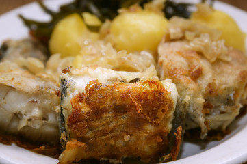 Fried fish and boiled potatoes on a plate.