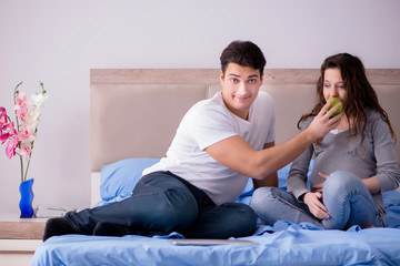 Young family with pregnant wife expecting baby in bed