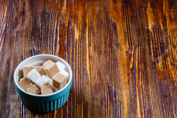 Сeramic sugar bowl with cane and white sugar on a wooden table