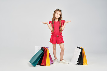 Little girl is standing around shoppers bags