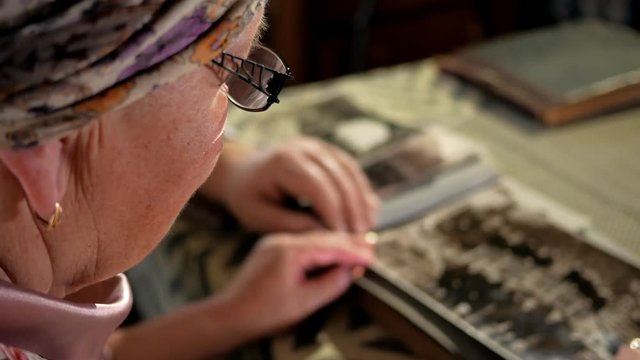 An elderly couple man and woman are looking at their old photos at home and talking. A man with a mustache, a wife with glasses