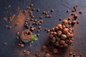 Hazelnut, coffee beans and cocoa powder in dark background.