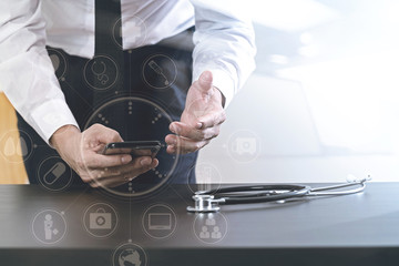 close up of smart medical doctor working with smart phone and stethoscope on dark wooden desk with virtual icon diagram