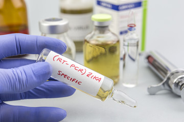 Scientist with blue latex gloves holds vials of ZIKA virus in laboratory for analysis