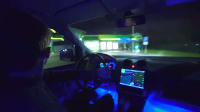 The man drive a car on the gas station. evening night time. inside view, real time capture