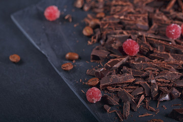 Dark chopping chocolate, black roasted coffee beans, red berries on dark background