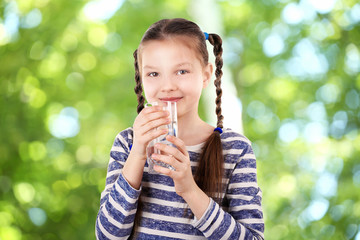 Little girl with glass of clean water on blurred background