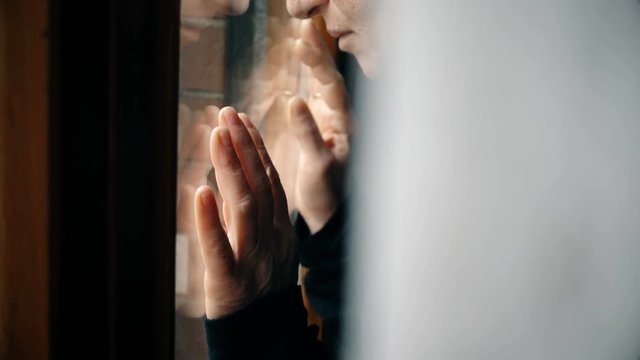 Desperate sad woman's hands  on window, close up