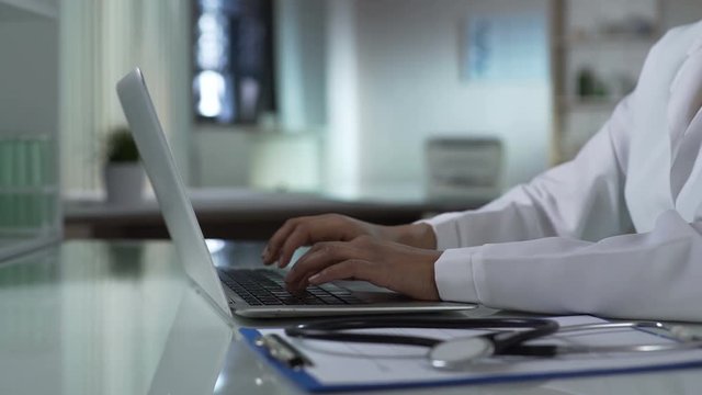Physician starts typing on laptop, keeping patients medical record, healthcare