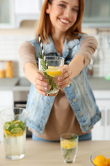 Beautiful young woman with lemonade in kitchen