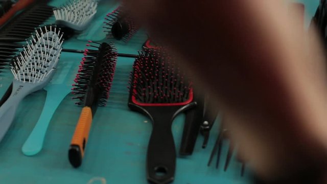 Close-up hand of hairdresser takes a combs at professional hair salon.