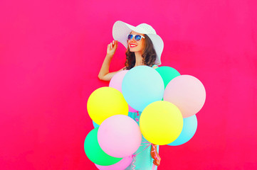 Fashion happy pretty smiling woman with an air colorful balloons is having fun in summer over pink background