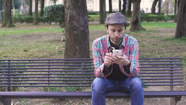 Man on the bench alone receives a message on smartphones and exults