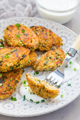 Vegetarian quinoa, carrot, coriander and green onion fritters served with yogurt on plate, vertical