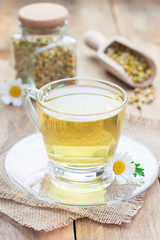 Chamomile tea in glass cup, chamomile flowers and dry tea on background, vertical