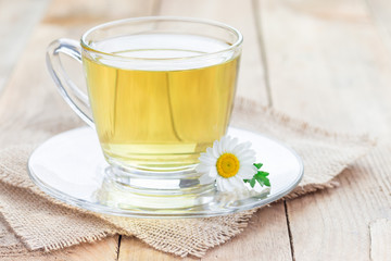 Chamomile tea in glass cup on wooden background, horizontal, copy space
