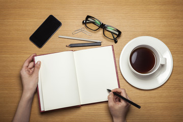 woman hand hold a note with coffee on the wood background(desk, table)