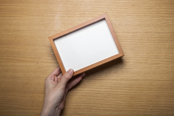 Obraz premium woman hand hold a photo frame on the wood table(background)