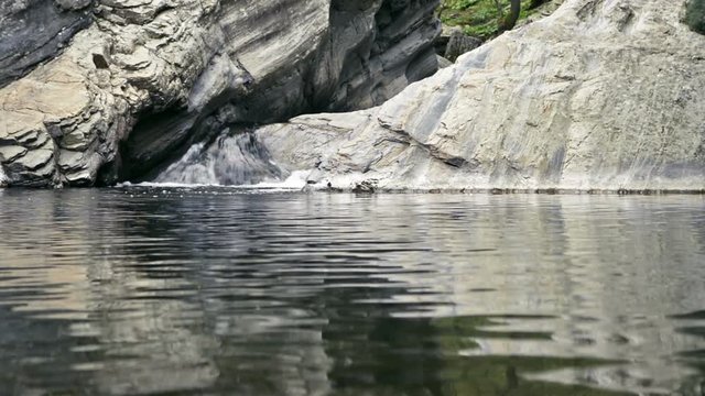 Small waterfall, rocks and poddle with reflection HD footage.