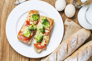 open sandwich with prosciutto, mozzarella and tomatoes on kitchen table, shallow focus