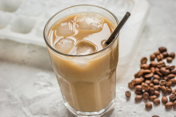 cold coffee glass with ice cubes on stone table background