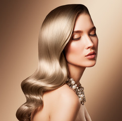 Beautiful model girl with long wavy and shiny hair . Woman with curly hairstyle. Face with clean fresh skin close up.