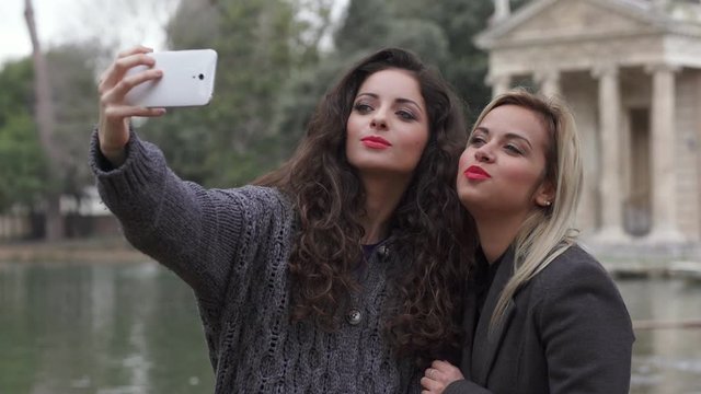 Making Selfie In The Park: Two beautiful Women Making A Selfie