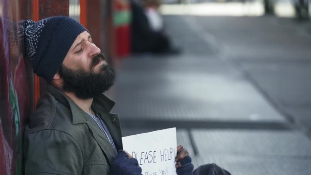 Sad Beggar profile begs alms in the street