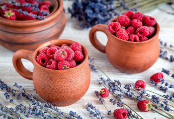 raspberry in pottery cup with lavander on wooden background