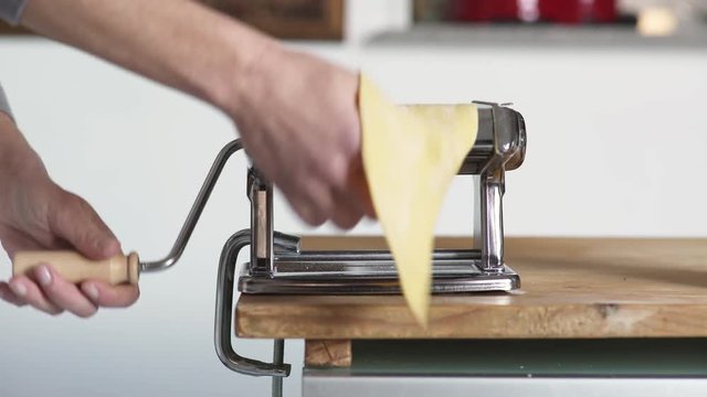 woman's hand Passing the dough into the machine to flatten it