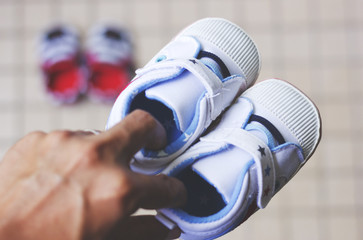 A father holding a pair of shoe for his newborn baby.