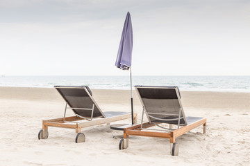 Beach chairs and umbrella on the white sand beach in evening time, relaxation and vacation time.