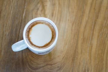 Hot coffee in the large white cup on the wooden table background
