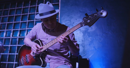 Fototapeta premium Guitarist at scene in bar - musician in hat plays guitar
