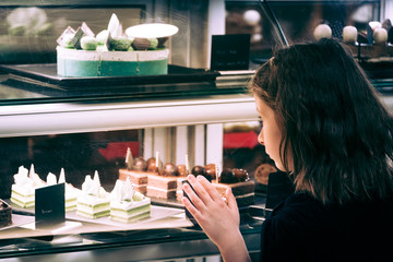 Little girl in confectionary shop looking at the display. Sweet treats variety. Small business and child concept