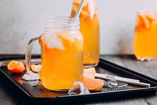 Citrus iced tea with lemon and mandarin in mason jar on table. Summer drink