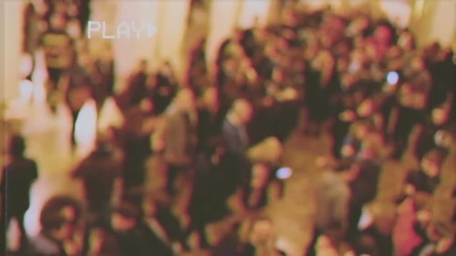 Fake VHS tape: a flow of blurred people moving in a hall before or after a concert.
