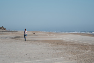 Fototapeta na wymiar Woman walking alone, during the day, on a beach in Florida