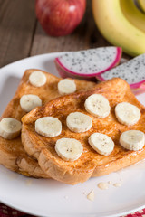 French toast topped with sliced banana, honey and fruit.