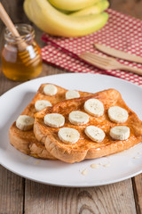 French toast topped with sliced banana, honey and fruit.