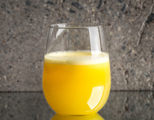 Glass of fresh orange juice on concrete background