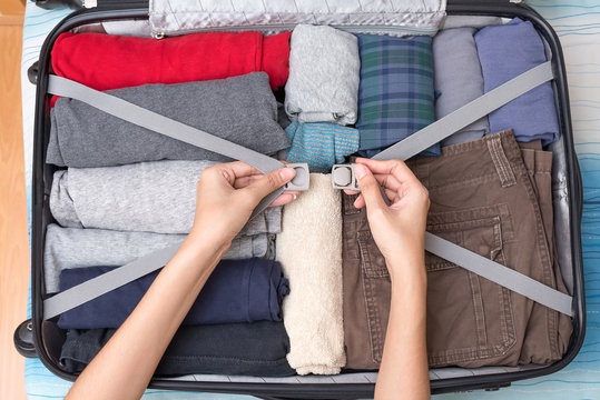 Woman's hands are packed suitcase on bed.
