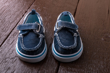 Blue boat shoes on brown wooden background. Boy footwear